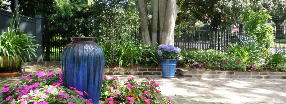new orleans courtyard with blue urn pink flowers